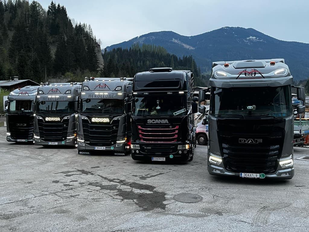 Fünf Lkw der Flotte vor Berglandschaft